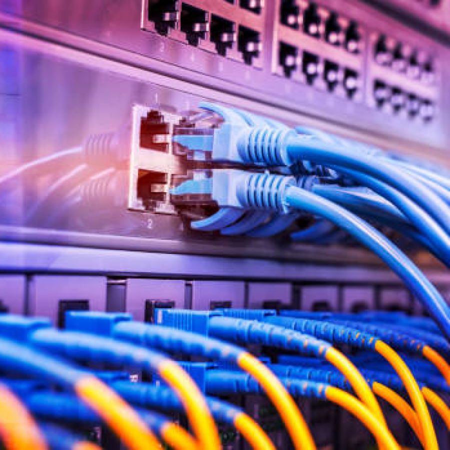 Server rack with blue and red internet patch cord cables connected to black patch panel in data server room